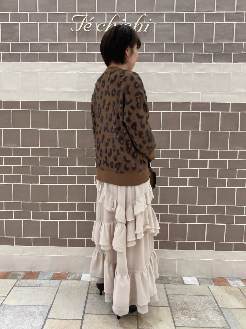 ブラウン系のニット/セーター、ベージュ系のスカート、ブラウン系のブーツを着用したレディースの秋コーディネートの3枚目の写真