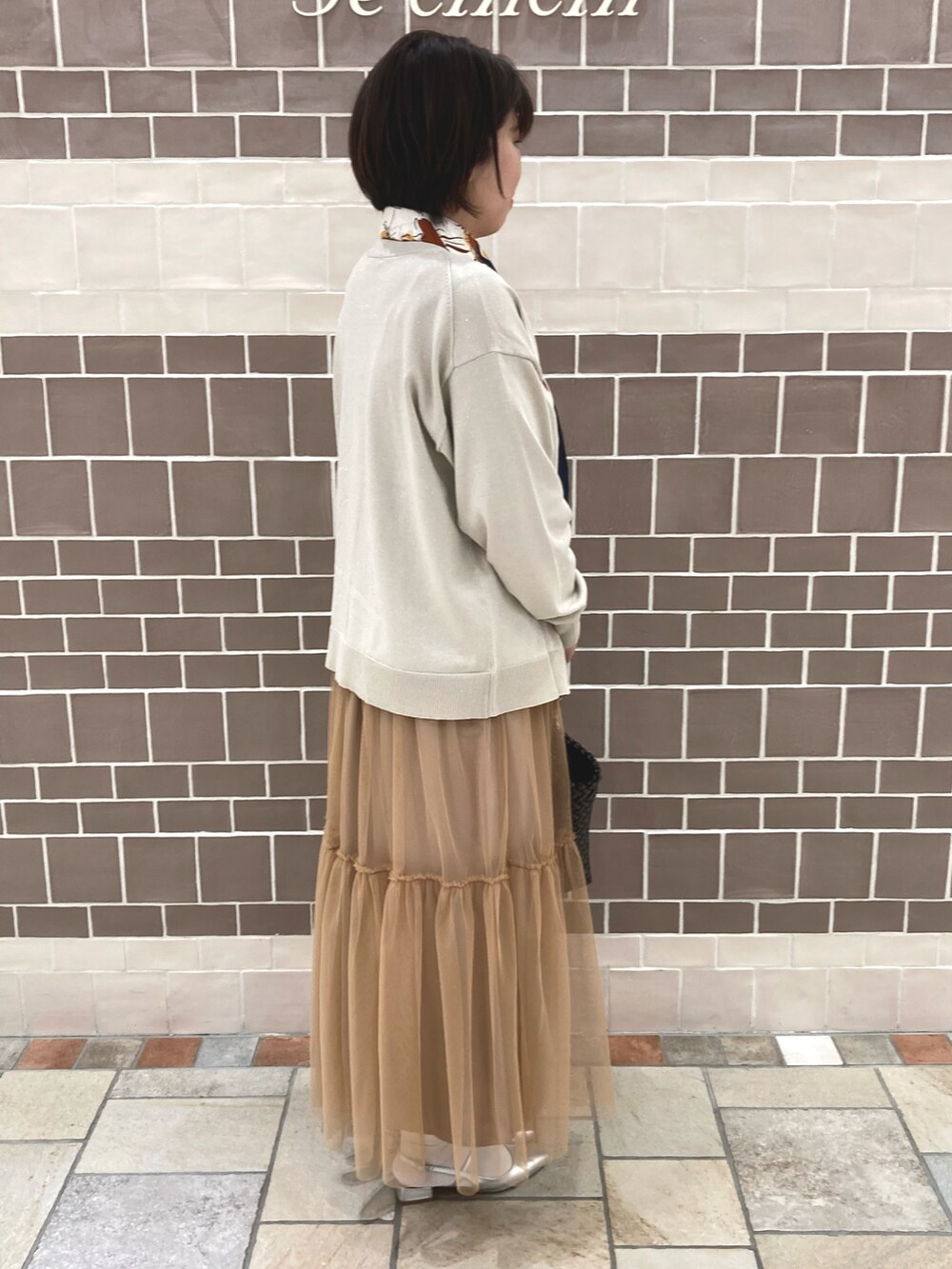 ブラウン系のワンピース、シルバー系のカーディガン/ボレロ、ブラウン系のトートバッグを着用したレディースの春コーディネートの3枚目の写真