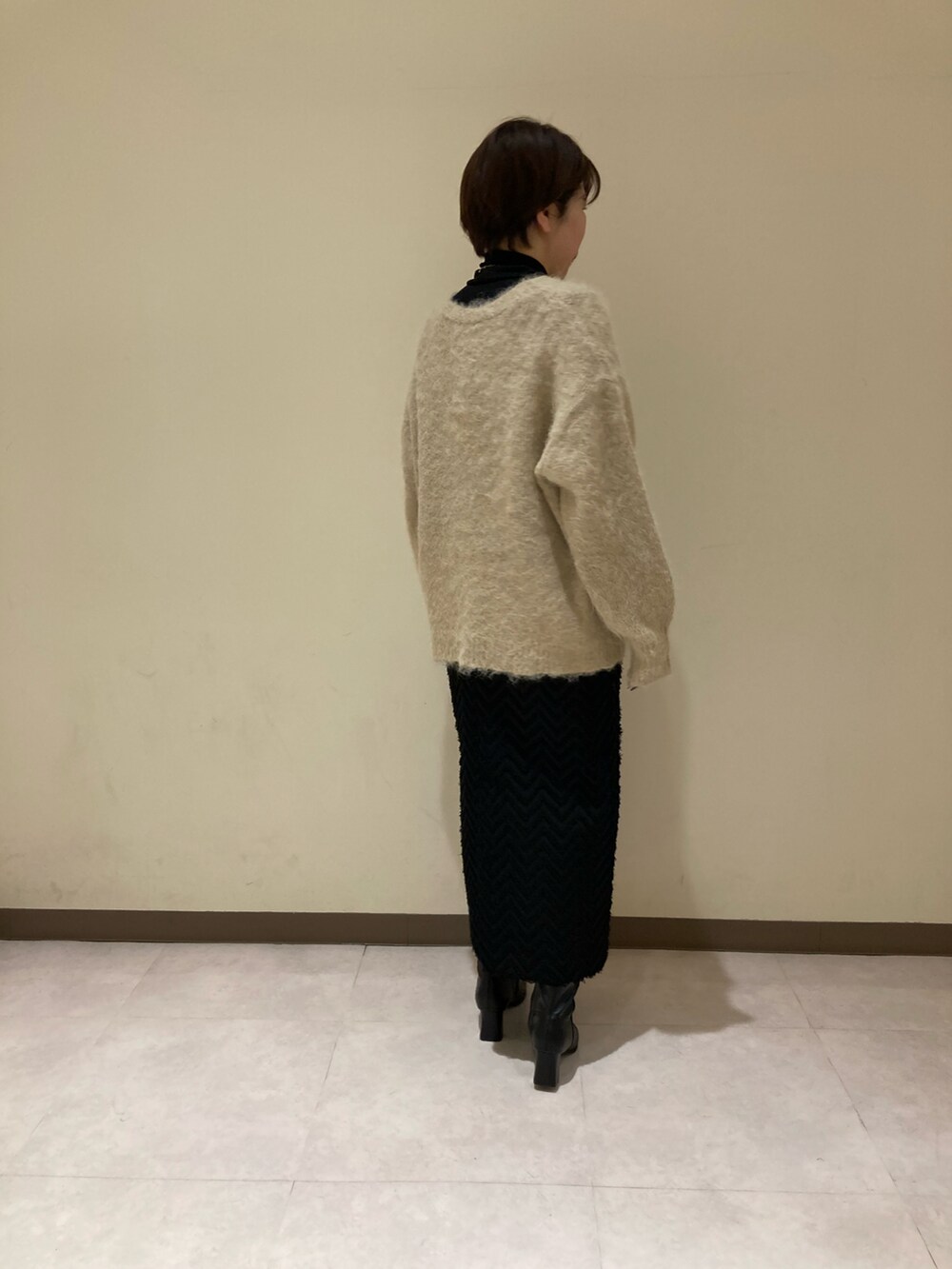 ベージュ系のカーディガン/ボレロ、ブラック系のスカート、ブラック系のブーツを着用したレディースの冬コーディネートの3枚目の写真