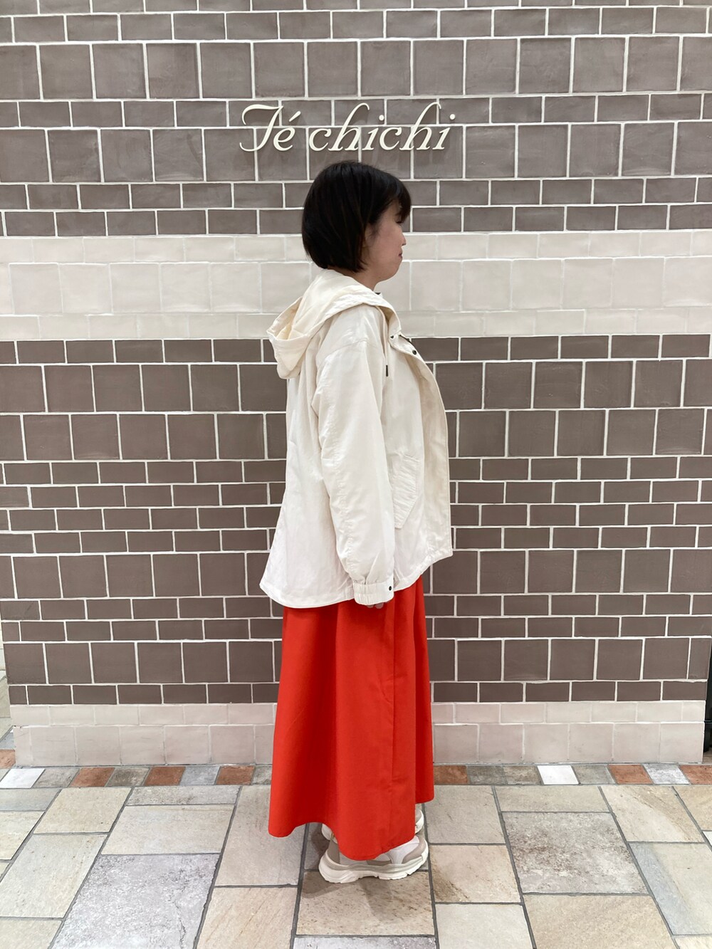 グレー系のTシャツ/カットソー、レッド系のスカート、ホワイト系のノーカラージャケットを着用したレディースの春コーディネートの2枚目の写真