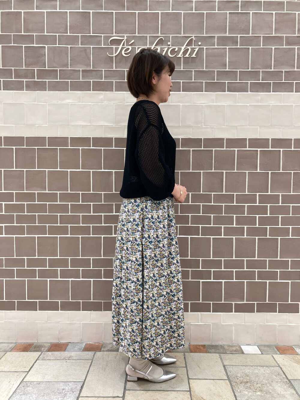 ブラック系のニット/セーター、ブルー系のスカート、シルバー系のパンプスを着用したレディースの春コーディネートの3枚目の写真