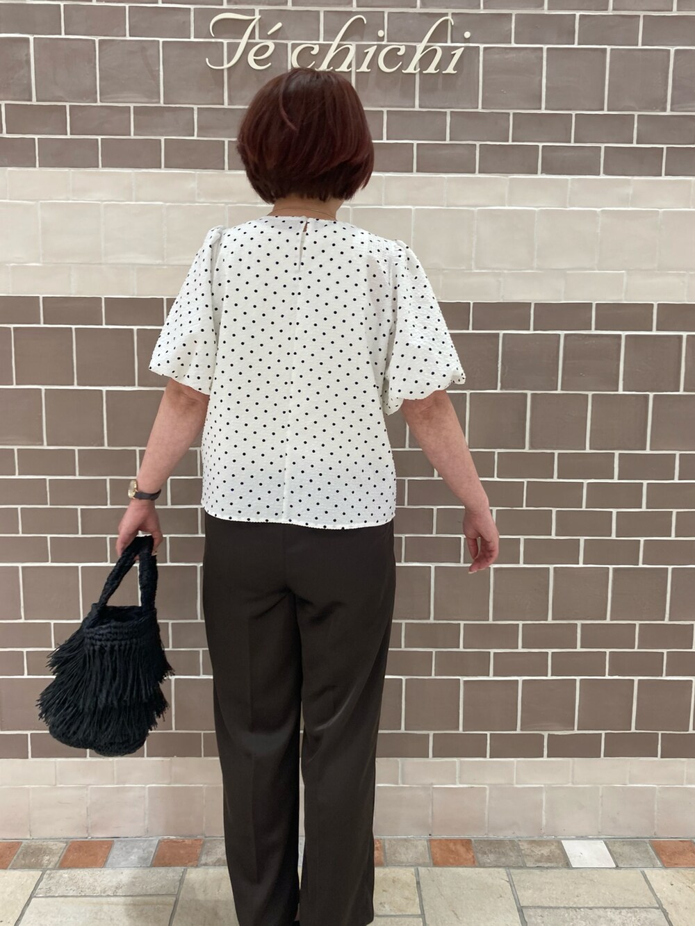 ホワイト系のシャツ/ブラウス、ブラック系のハンドバッグ、ブラウン系のパンツを着用したレディースの春コーディネートの3枚目の写真