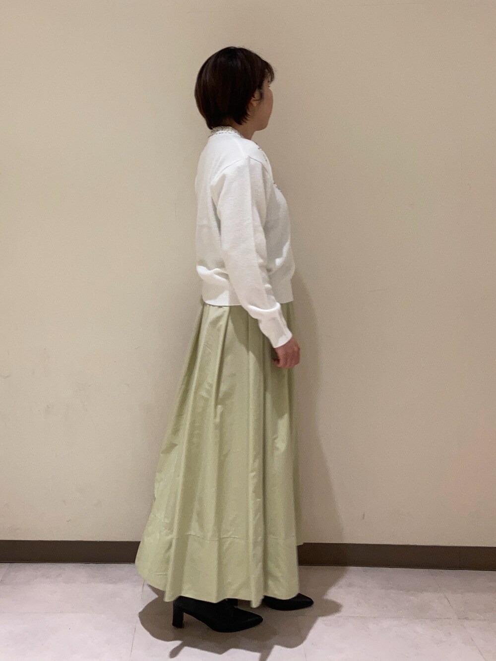 ホワイト系のニット/セーター、グリーン系のスカートを着用したレディースの冬コーディネートの2枚目の写真