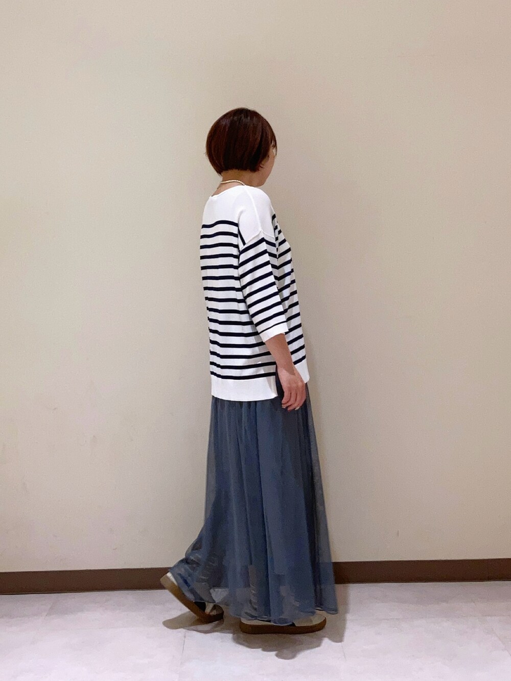 ホワイト系のニット/セーター、グレー系のスカートを着用したレディースの春コーディネートの2枚目の写真