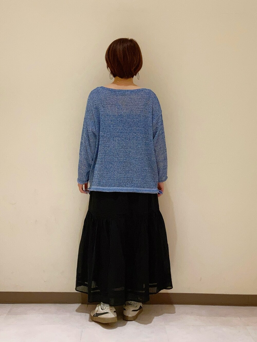 ブルー系のニット/セーター、ブラック系のスカートを着用したレディースの春コーディネートの4枚目の写真