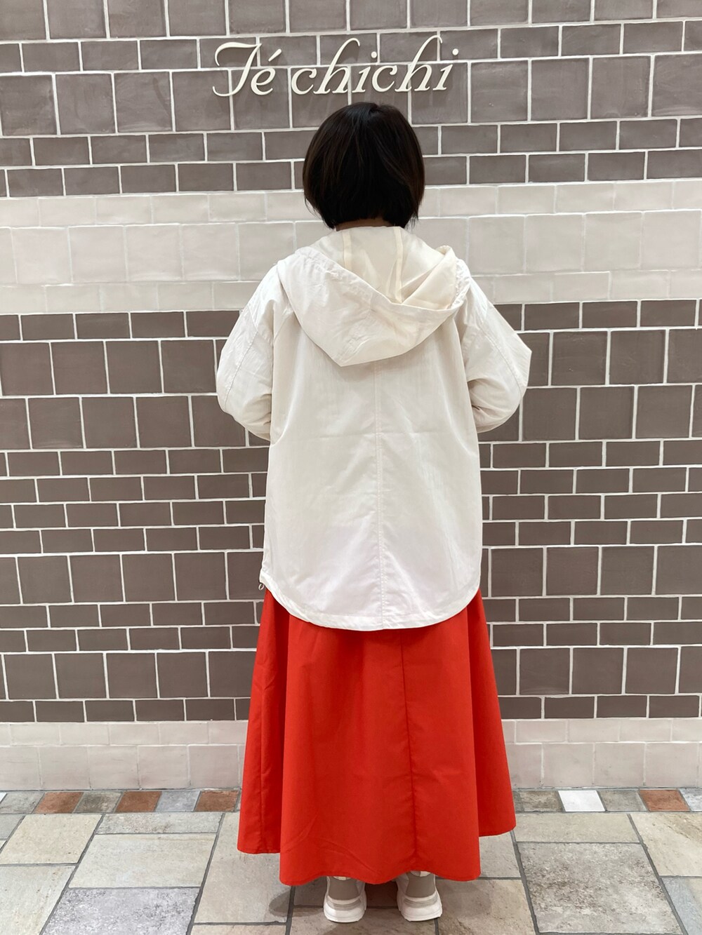 グレー系のTシャツ/カットソー、レッド系のスカート、ホワイト系のノーカラージャケットを着用したレディースの春コーディネートの3枚目の写真