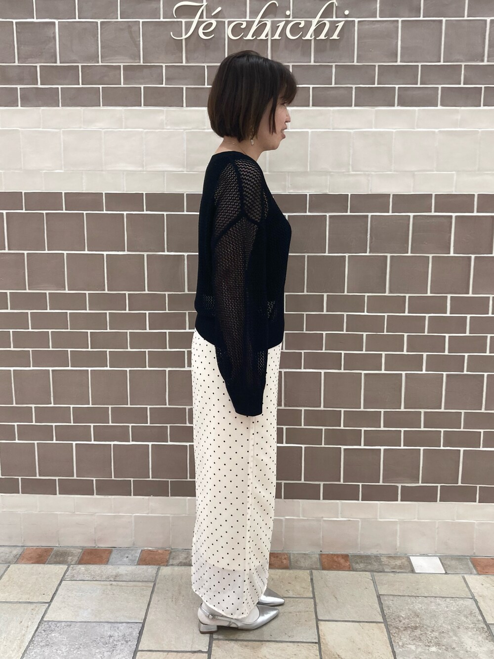 ブラック系のニット/セーター、ベージュ系のスカート、シルバー系のパンプスを着用したレディースの春コーディネートの3枚目の写真