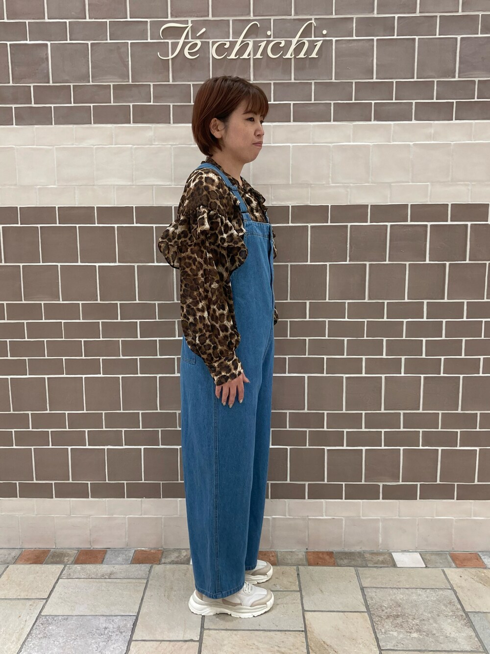 ブルー系のサロペット/オーバーオール、ブラウン系のシャツ/ブラウス、ブラウン系のスニーカーを着用したレディースの夏コーディネートの3枚目の写真