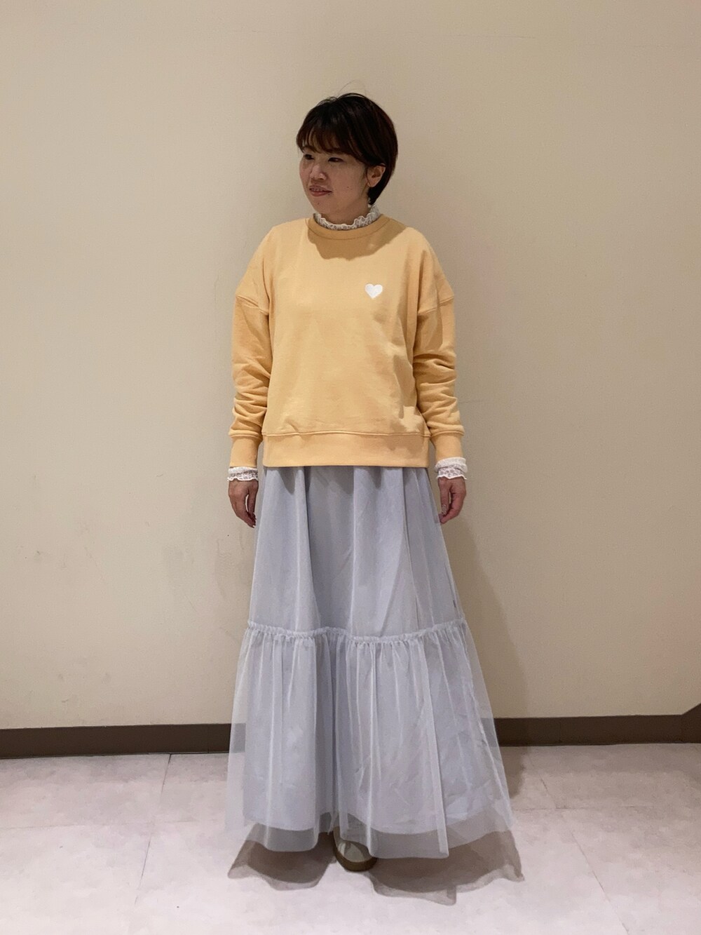 オレンジ系のTシャツ/カットソー、グレー系のスカート、ホワイト系のTシャツ/カットソーを着用したレディースの冬コーディネートの2枚目の写真