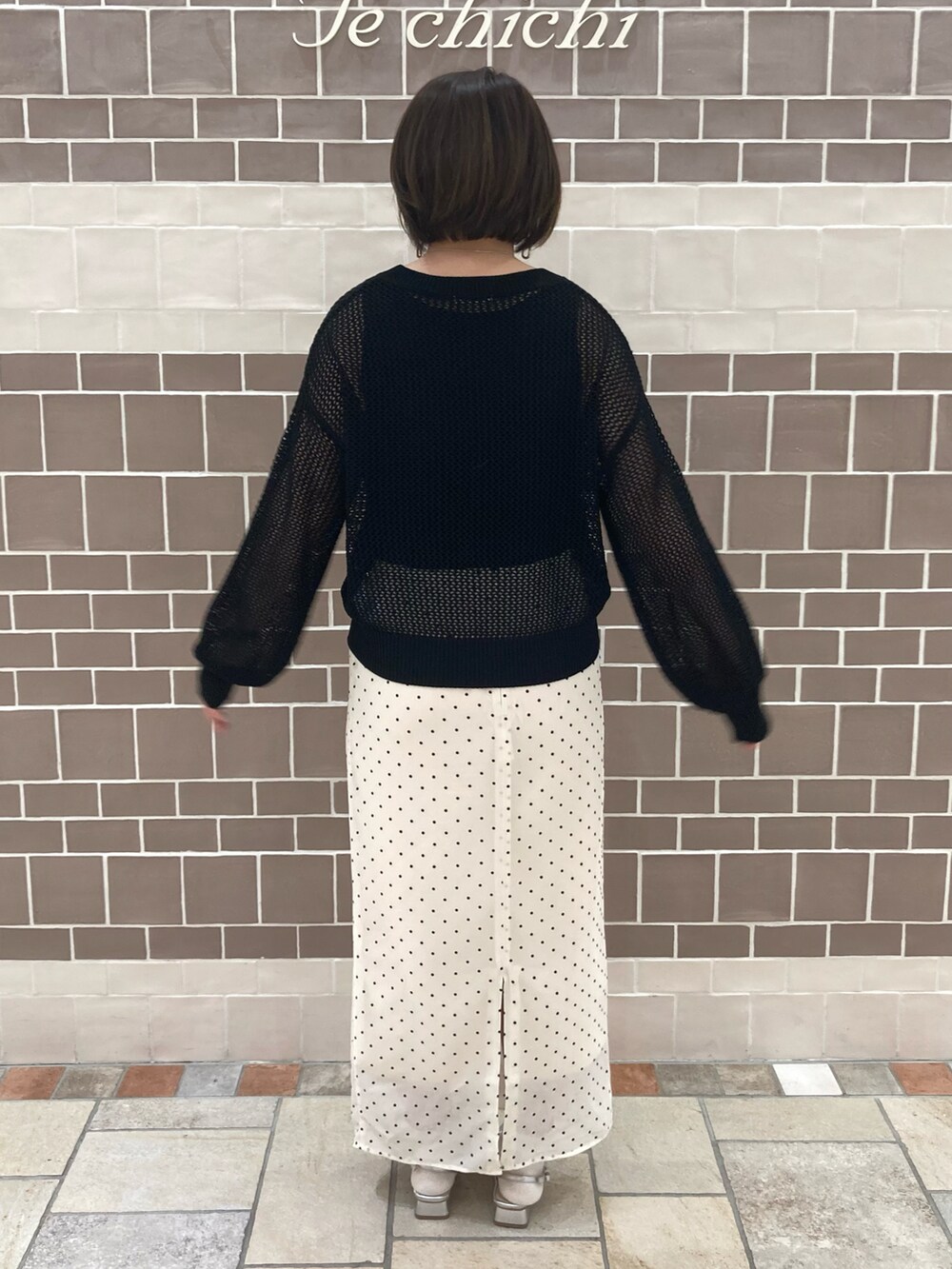 ブラック系のニット/セーター、ベージュ系のスカート、シルバー系のパンプスを着用したレディースの春コーディネートの4枚目の写真