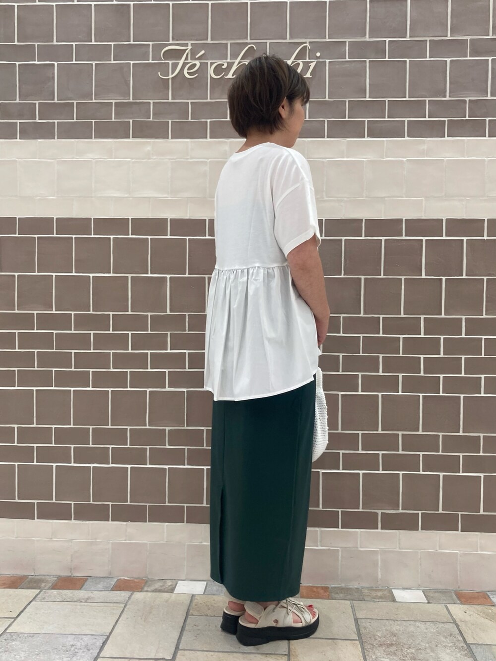 ホワイト系のTシャツ/カットソー、グリーン系のスカート、ホワイト系のハンドバッグを着用したレディースの夏コーディネートの3枚目の写真