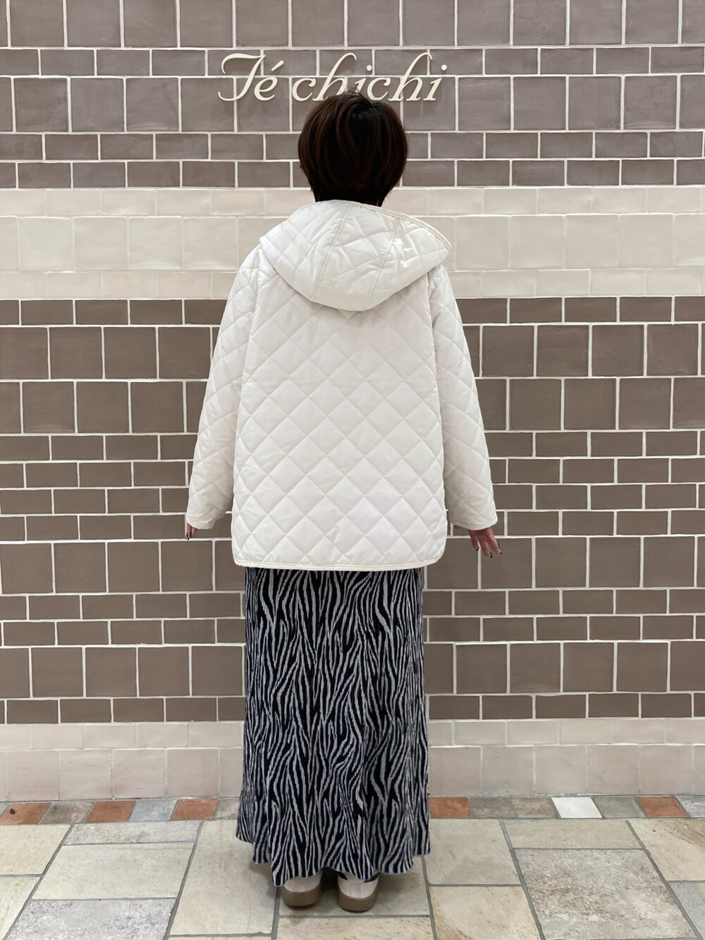 オレンジ系のニット/セーター、ホワイト系のその他アウター、ブラック系のスカートを着用したレディースの冬コーディネートの4枚目の写真