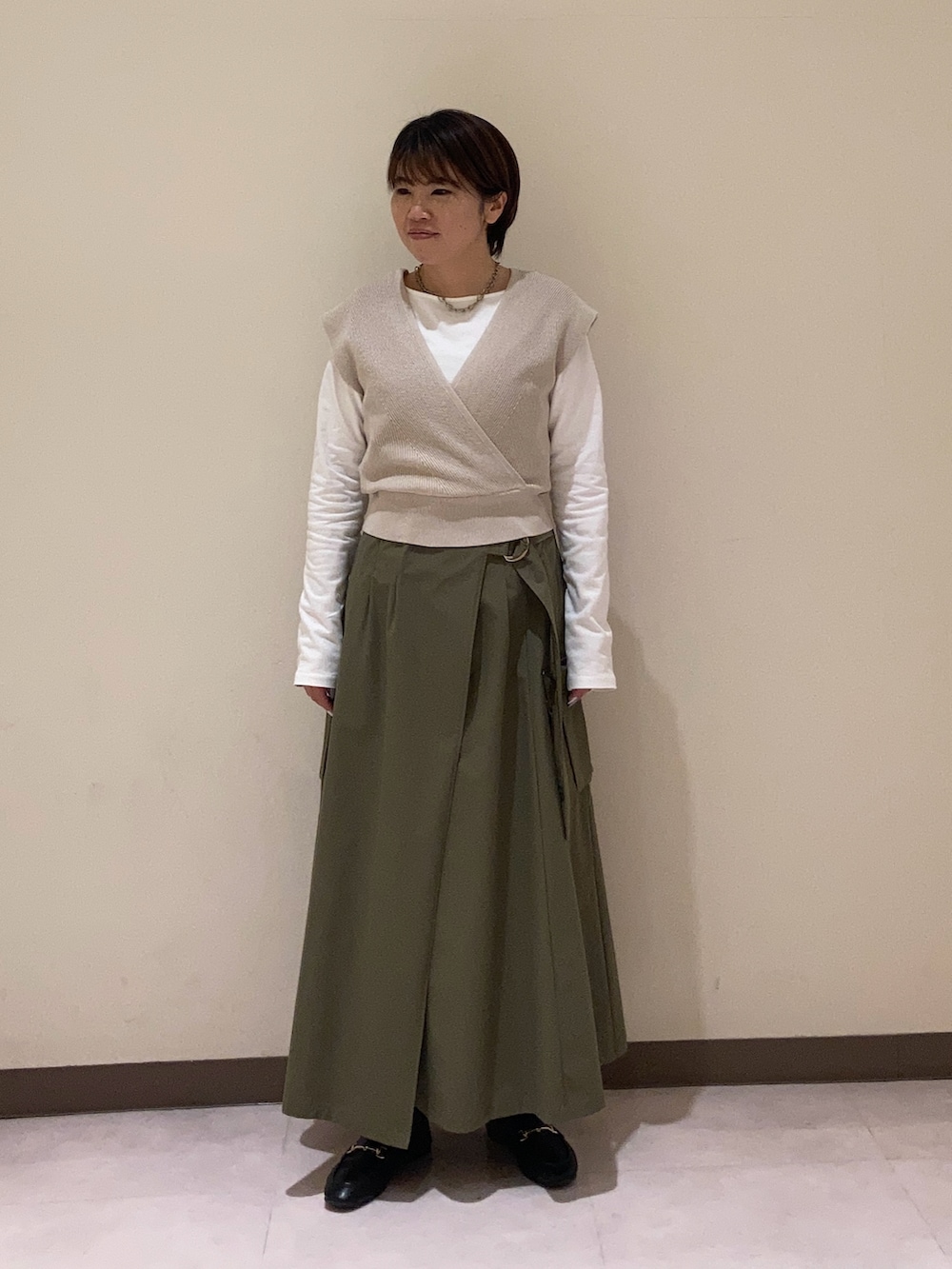 グリーン系のスカート、ベージュ系のベストを着用したレディースの冬コーディネートの2枚目の写真