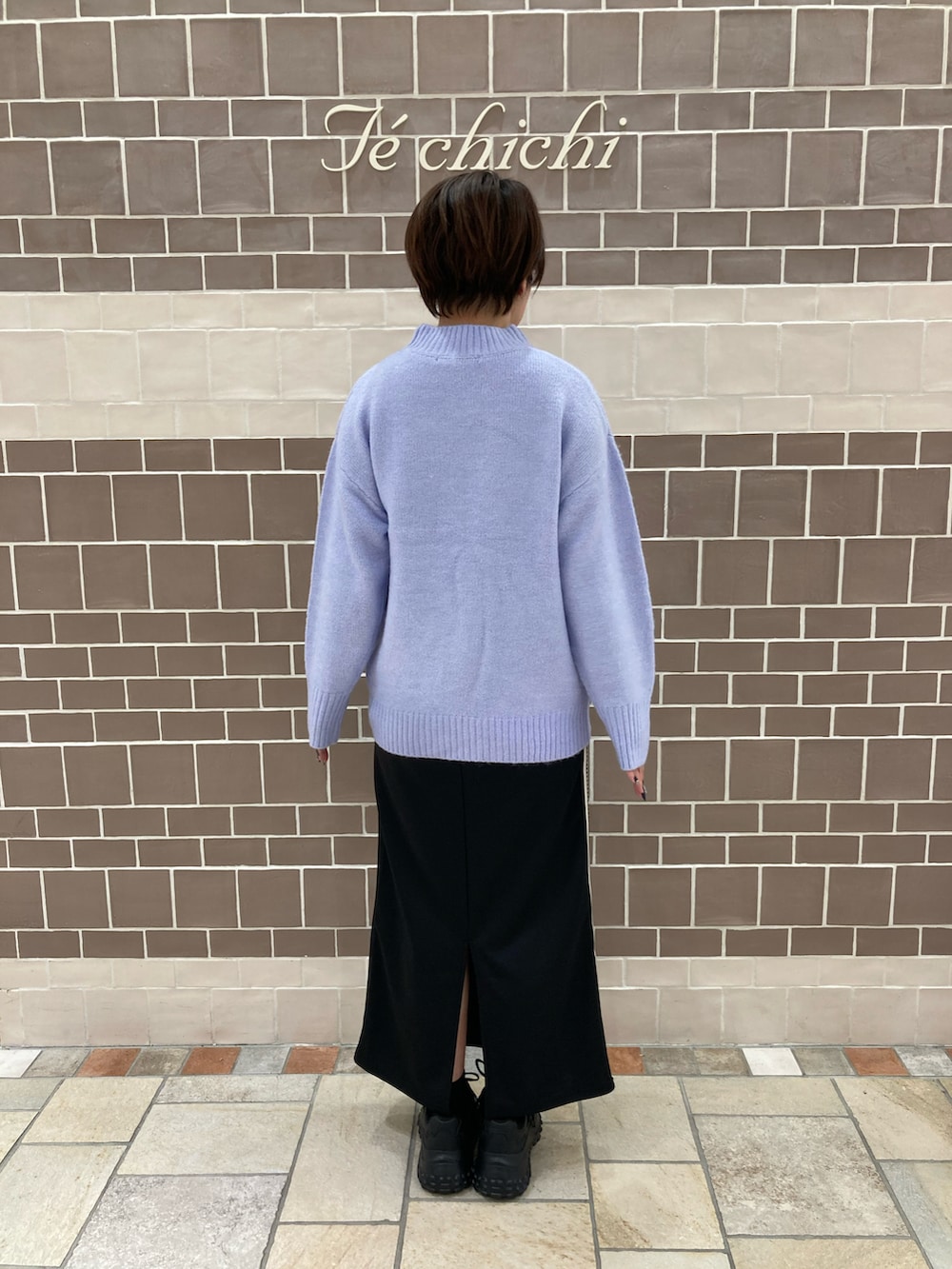 パープル系のニット/セーター、ブラック系のスカートを着用したレディースの冬コーディネートの3枚目の写真