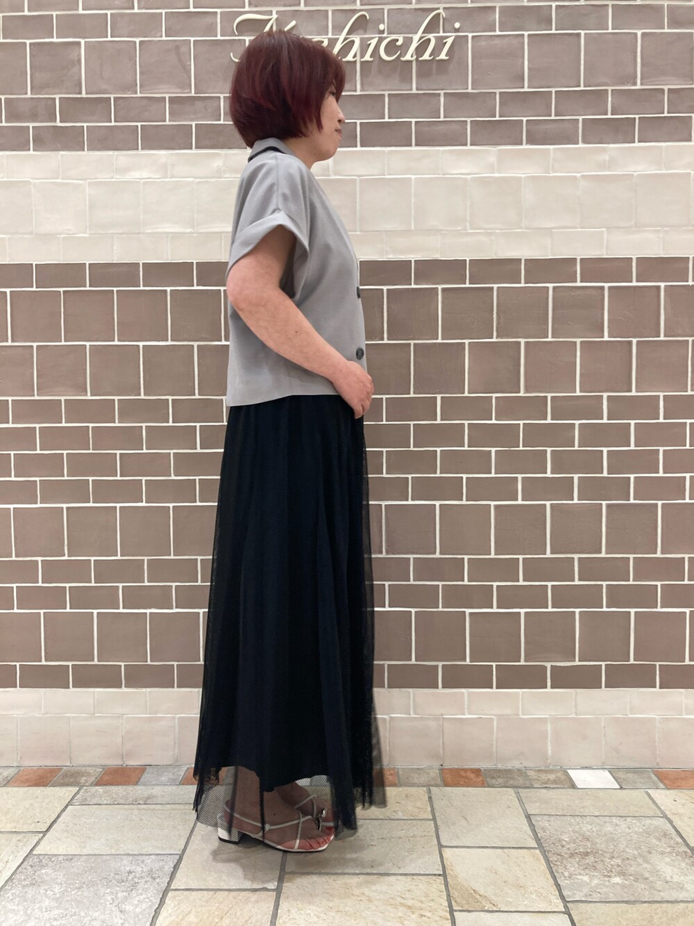 グレー系のノーカラージャケット、ブラック系のスカート、ホワイト系のサンダルを着用したレディースの夏コーディネートの3枚目の写真