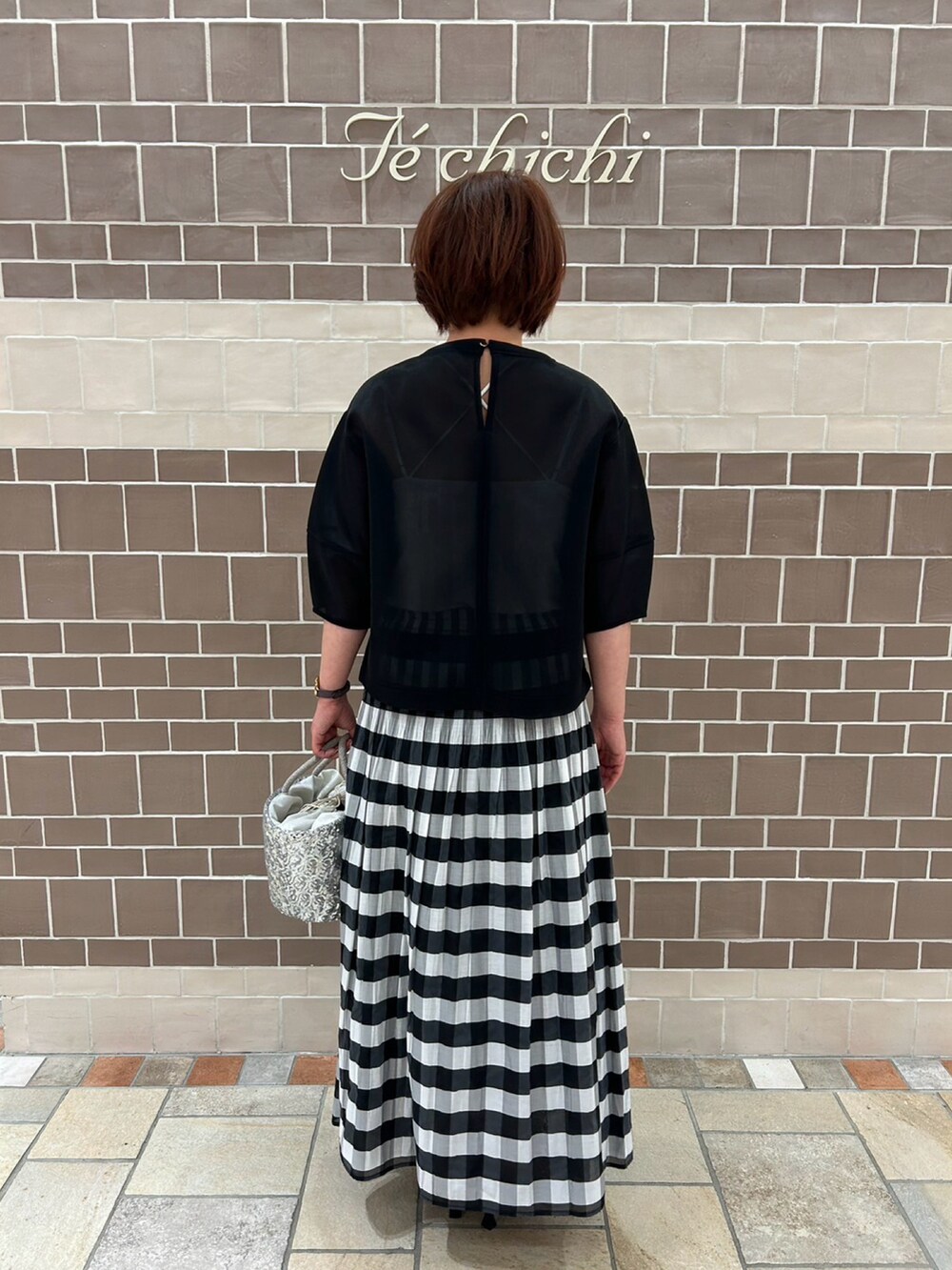 ブラック系のシャツ/ブラウス、ブラック系のスカート、シルバー系のハンドバッグを着用したレディースの春コーディネートの3枚目の写真