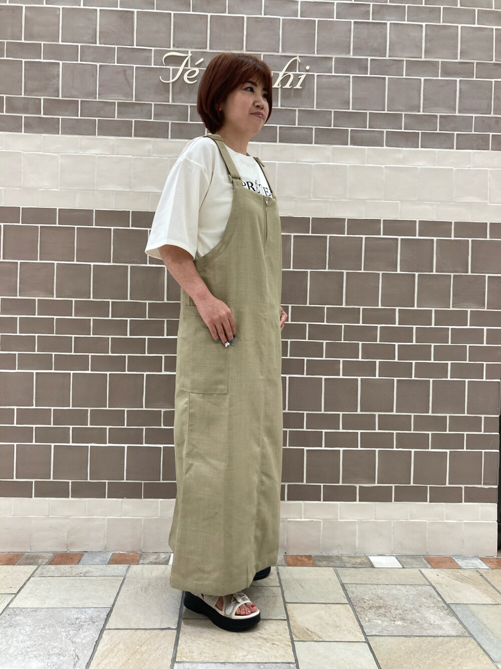 ベージュ系のワンピース、ホワイト系のTシャツ/カットソーを着用したレディースの夏コーディネートの2枚目の写真