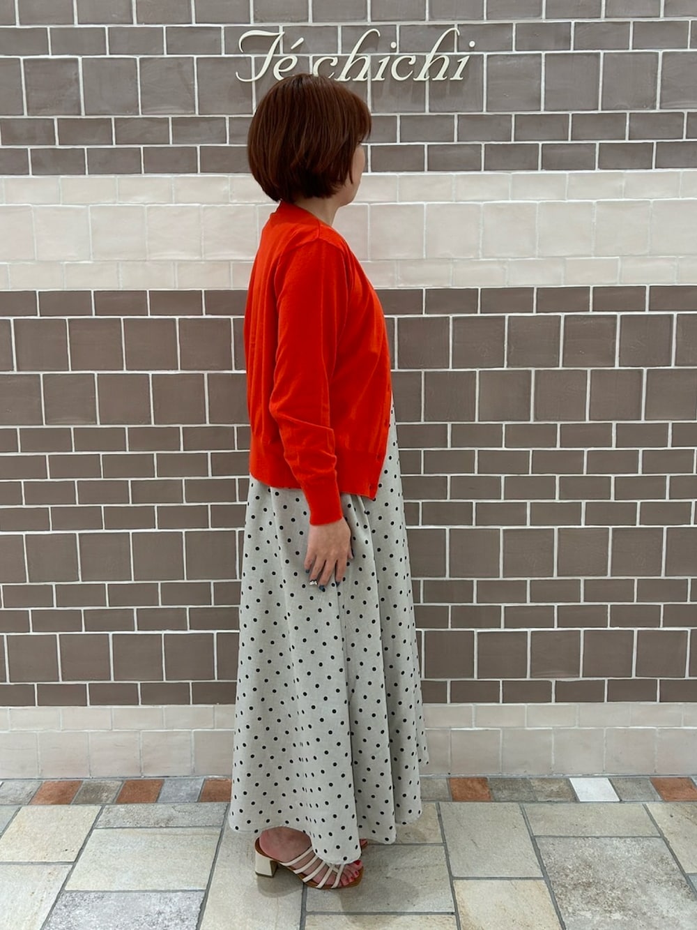 ベージュ系のワンピース/ドレス、レッド系のカーディガン/ボレロ、ホワイト系のサンダルを着用したレディースの夏コーディネートの4枚目の写真