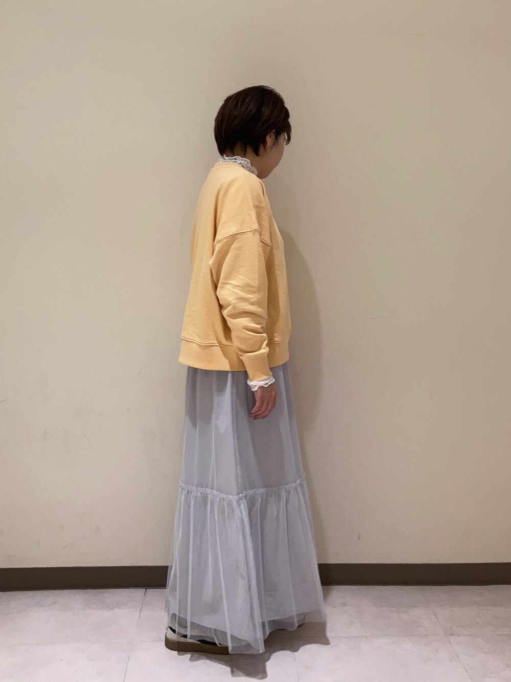 オレンジ系のTシャツ/カットソー、グレー系のスカート、ホワイト系のTシャツ/カットソーを着用したレディースの冬コーディネートの3枚目の写真