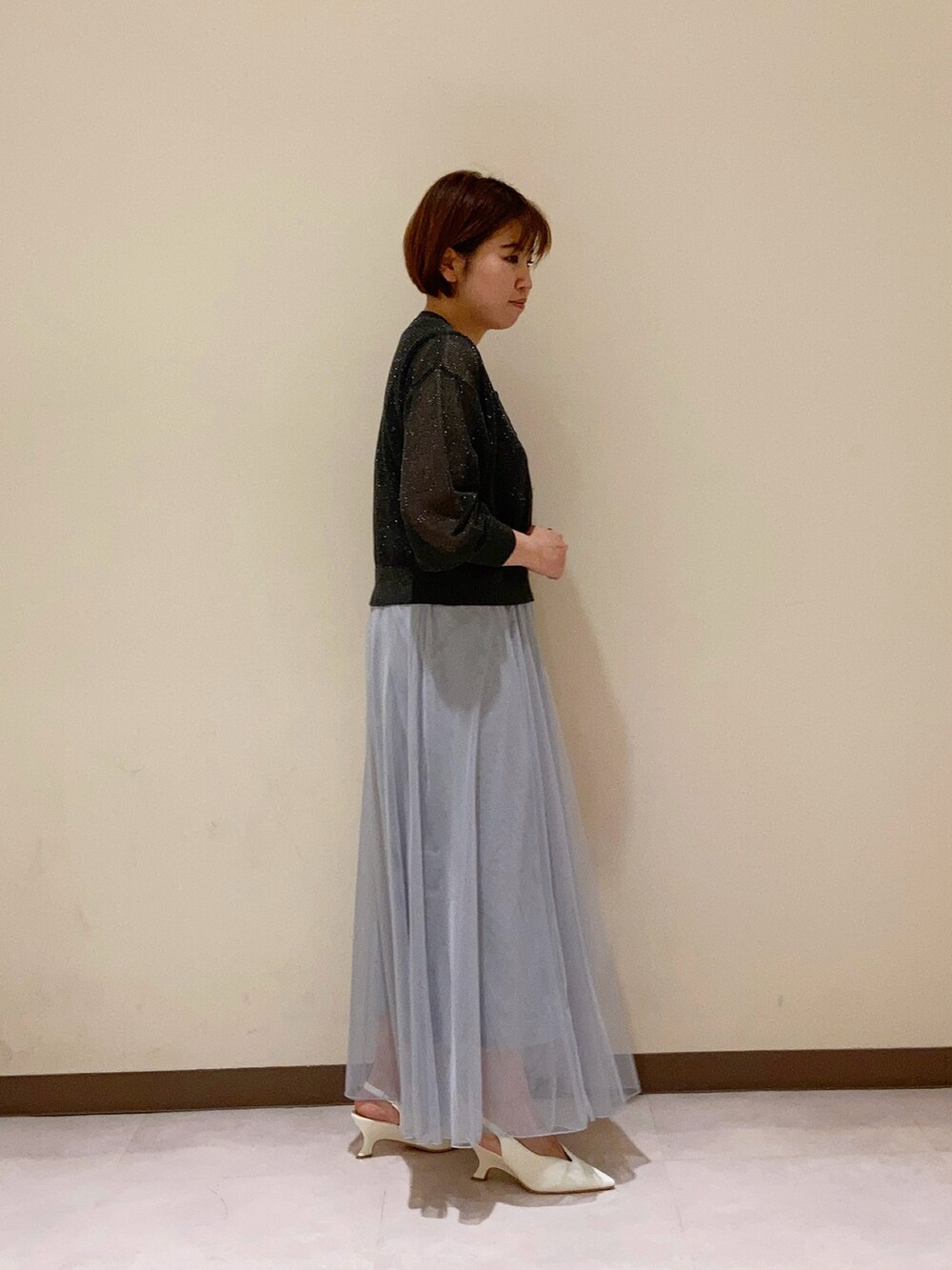 グレー系のカーディガン/ボレロ、グレー系のスカート、ブラック系のタンクトップを着用したレディースの春コーディネートの3枚目の写真