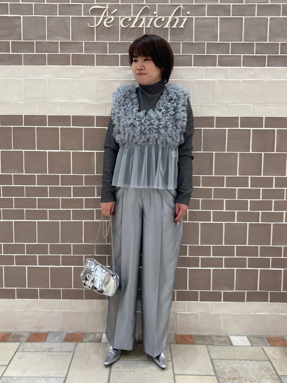 グレー系のニット/セーター、シルバー系のハンドバッグを着用したレディースの秋コーディネートの2枚目の写真