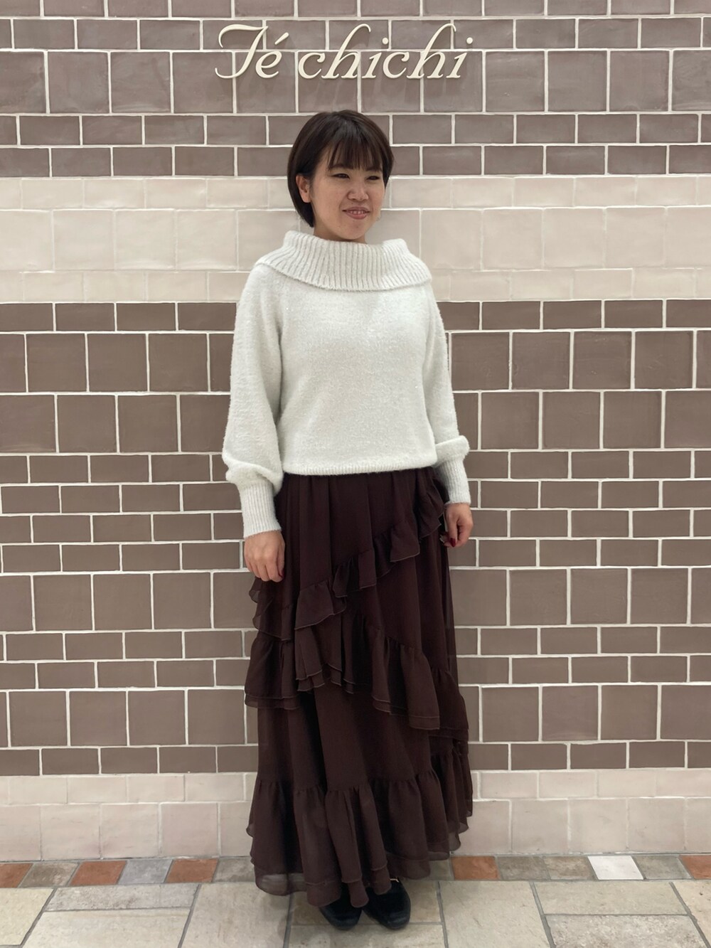 ホワイト系のニット/セーター、ブラウン系のスカートを着用したレディースの秋コーディネートの2枚目の写真