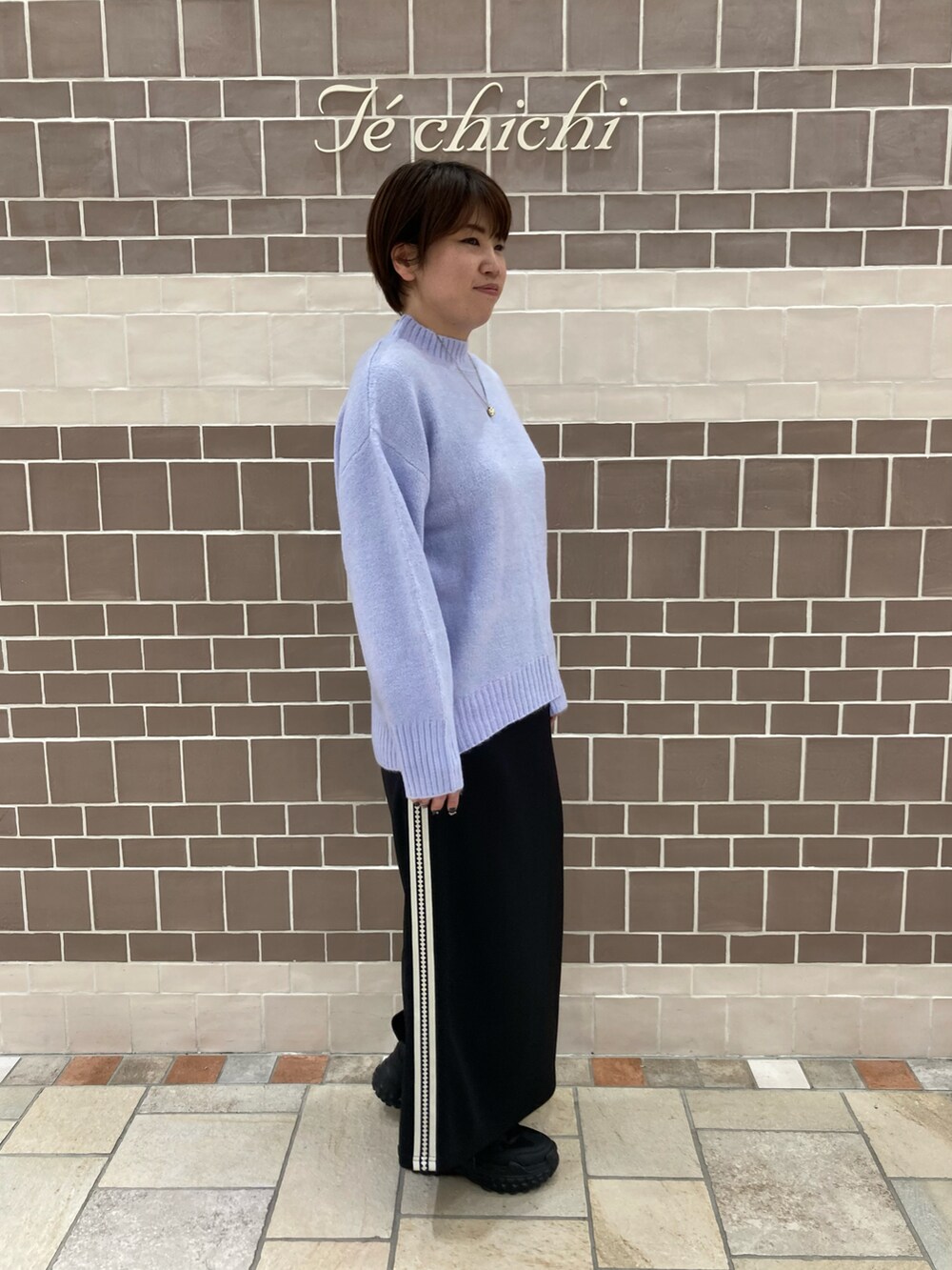 パープル系のニット/セーター、ブラック系のスカートを着用したレディースの冬コーディネートの2枚目の写真