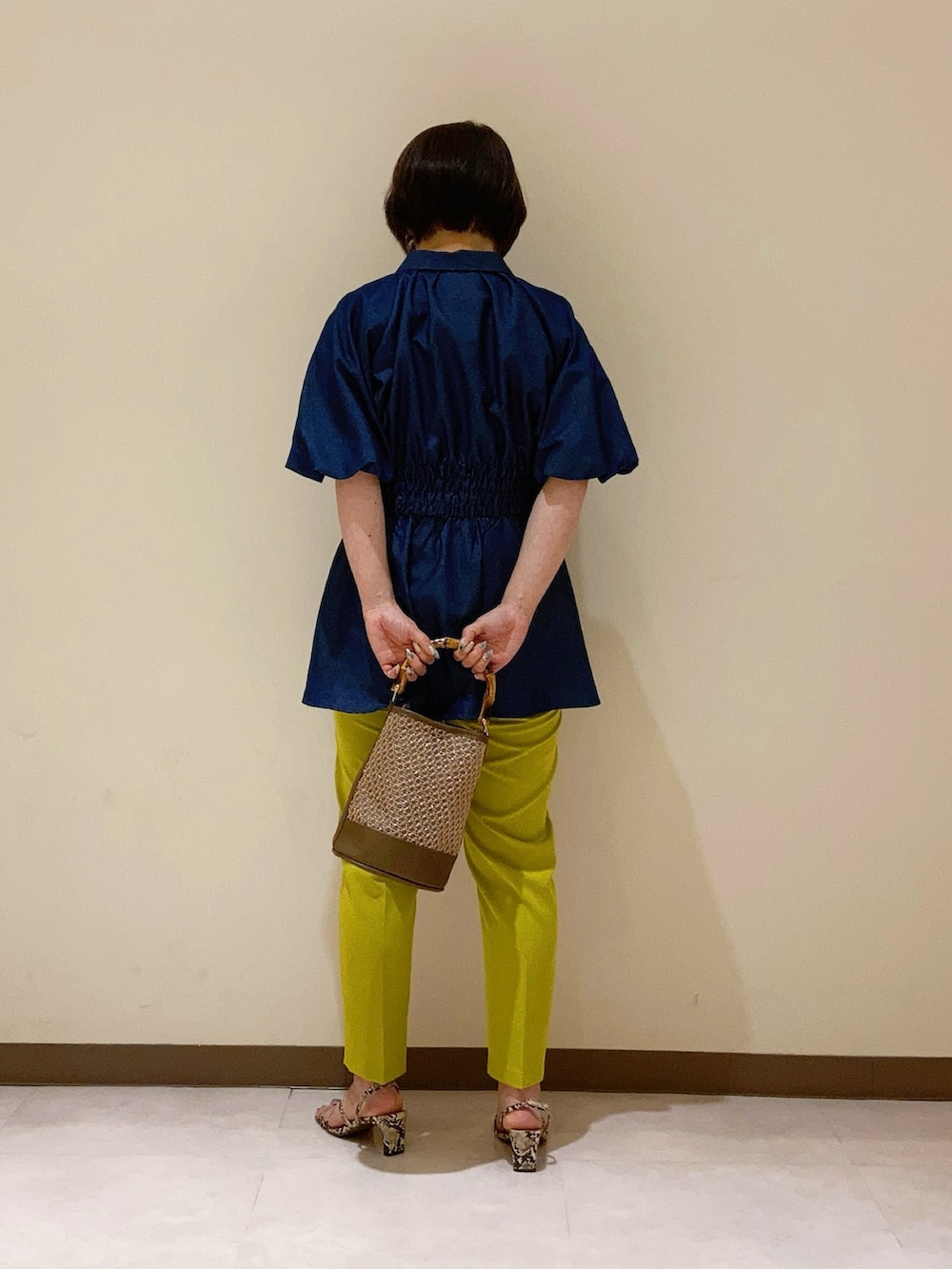 ブルー系のシャツ/ブラウス、イエロー系のパンツ、ブラウン系のハンドバッグを着用したレディースの春コーディネートの3枚目の写真