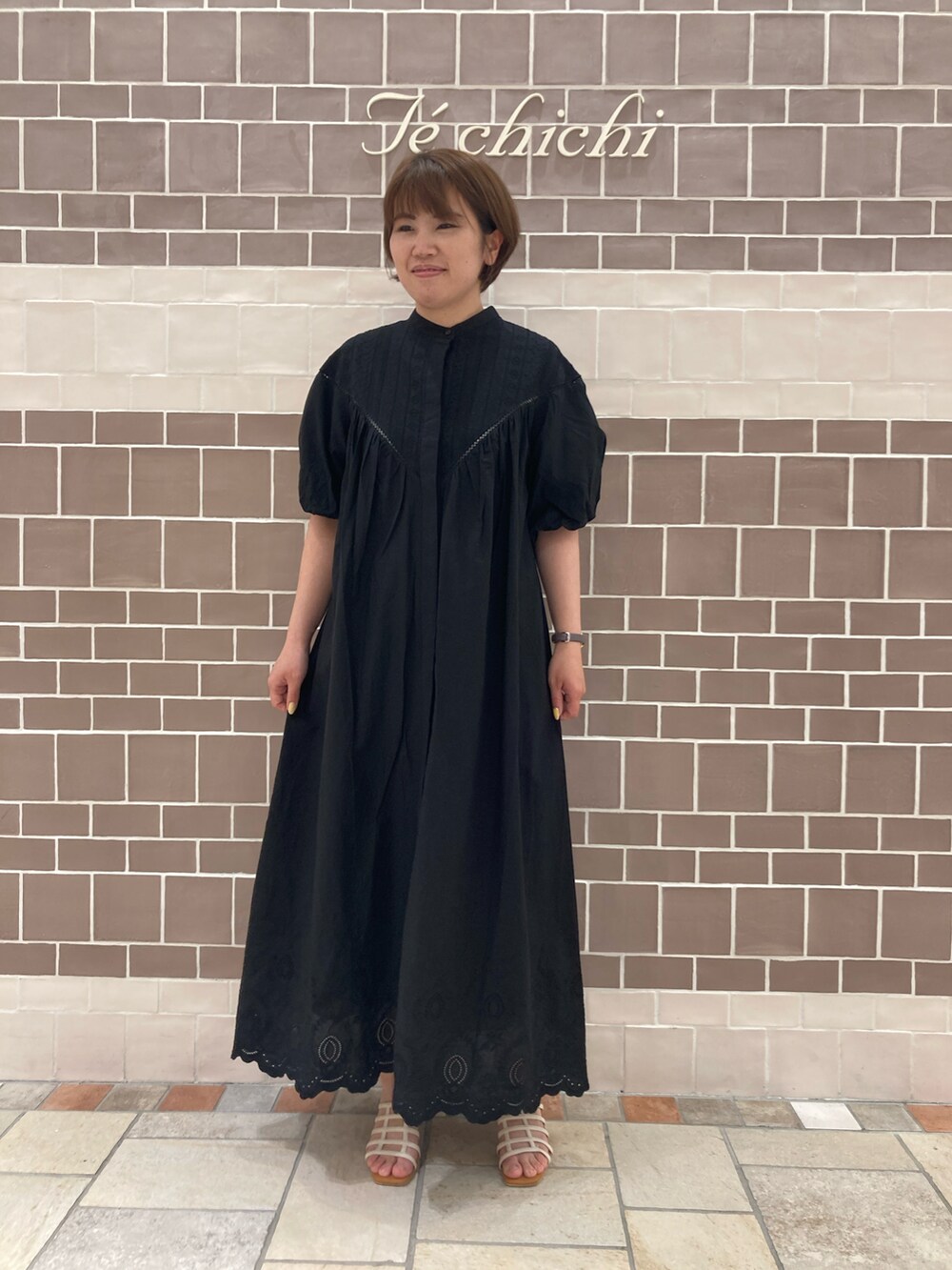 ブラック系のワンピース、ホワイト系のサンダルを着用したレディースの春コーディネートの2枚目の写真