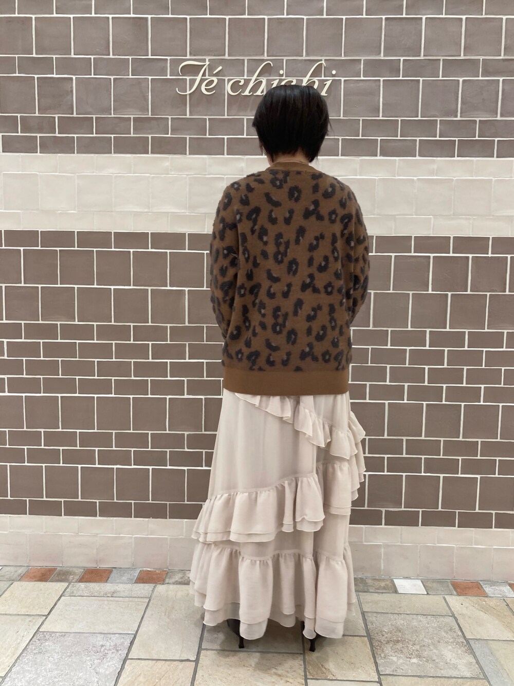 ブラウン系のニット/セーター、ベージュ系のスカート、ブラウン系のブーツを着用したレディースの秋コーディネートの4枚目の写真