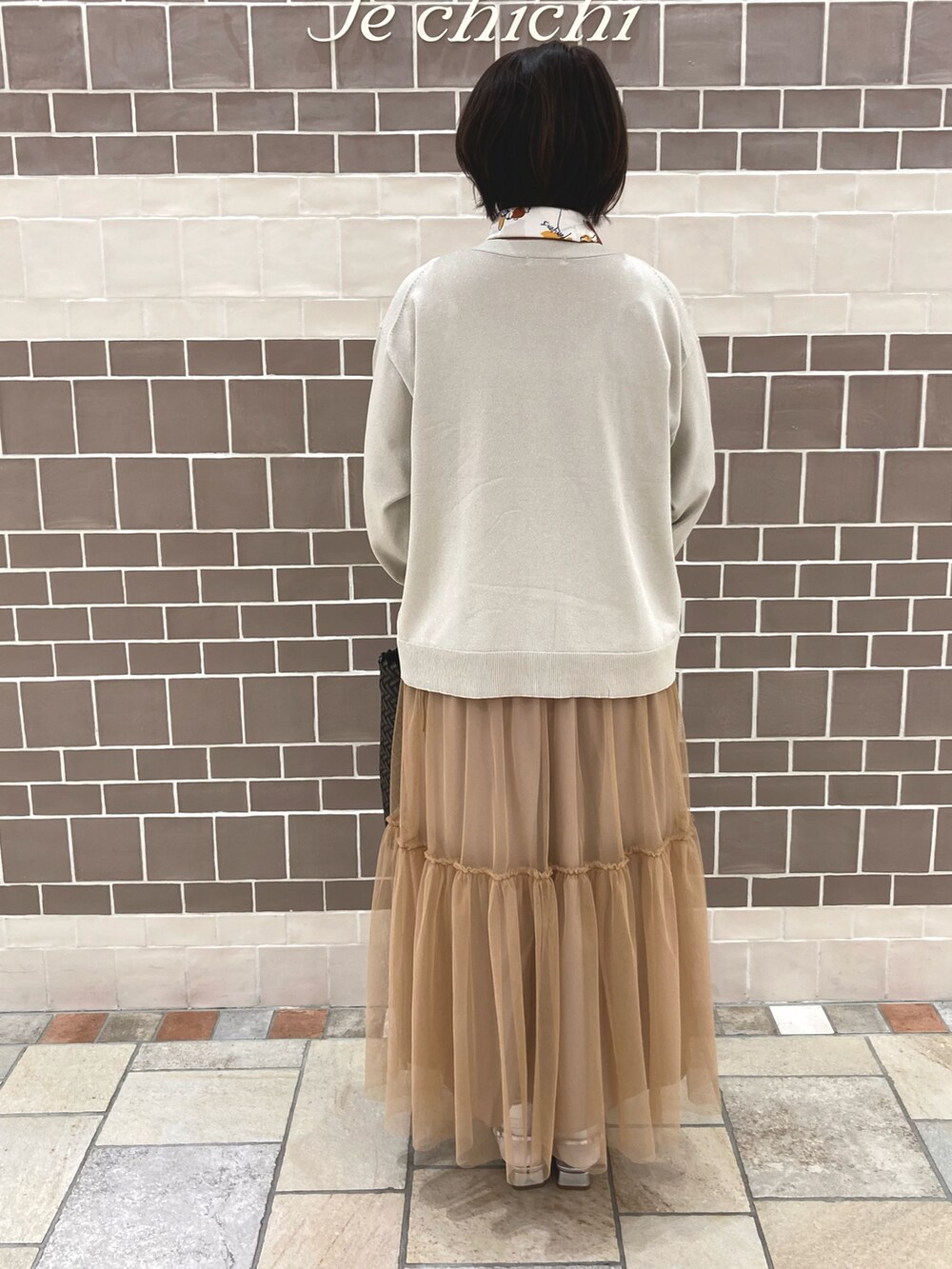 ブラウン系のワンピース、シルバー系のカーディガン/ボレロ、ブラウン系のトートバッグを着用したレディースの春コーディネートの4枚目の写真