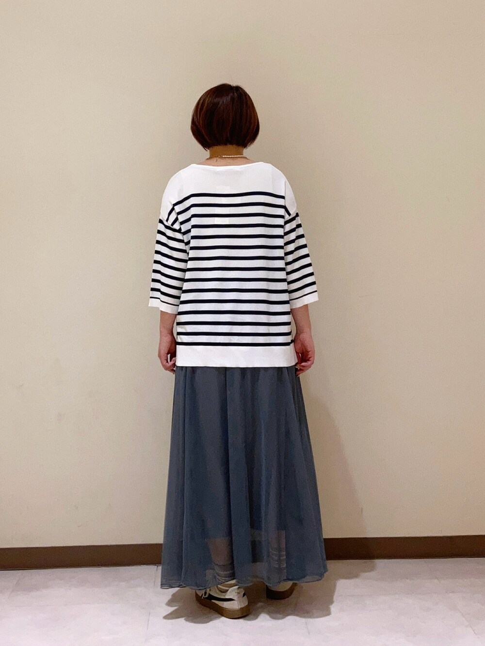 ホワイト系のニット/セーター、グレー系のスカートを着用したレディースの春コーディネートの3枚目の写真