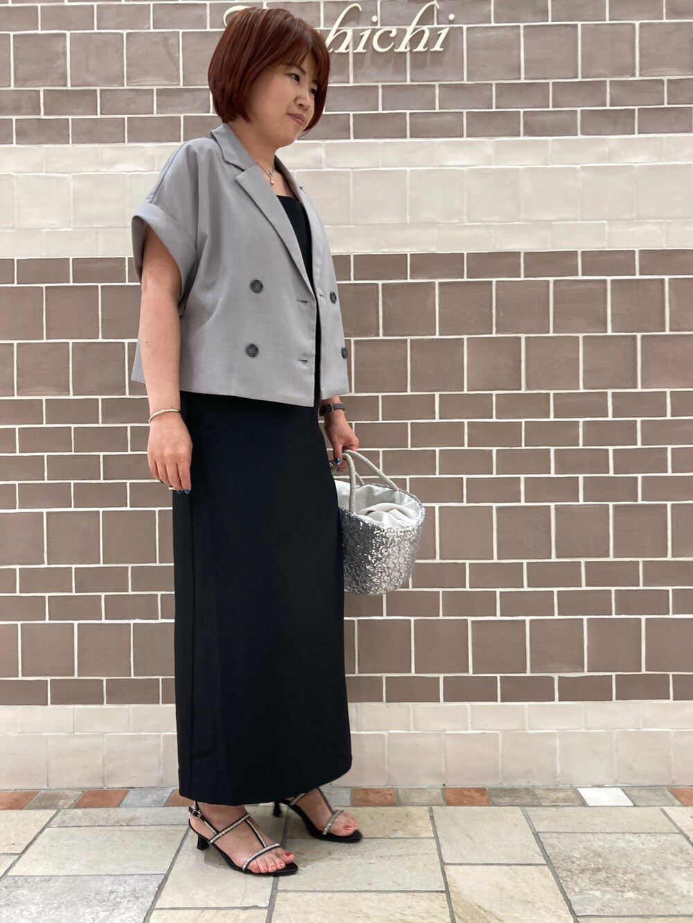 ブラック系のワンピース/ドレス、グレー系のノーカラージャケット、シルバー系のハンドバッグを着用したレディースの夏コーディネートの2枚目の写真