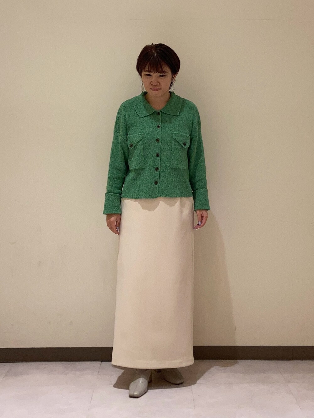 グリーン系のカーディガン/ボレロ、ベージュ系のスカートを着用したレディースの冬コーディネートの2枚目の写真