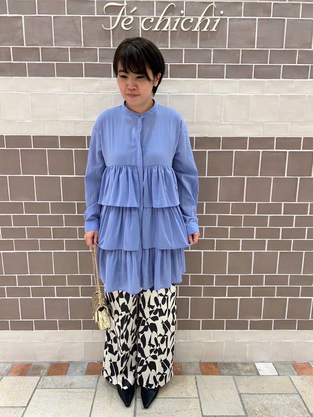 ブルー系のシャツ/ブラウス、ゴールド系のハンドバッグ、ホワイト系のパンツを着用したレディースの冬コーディネートの2枚目の写真