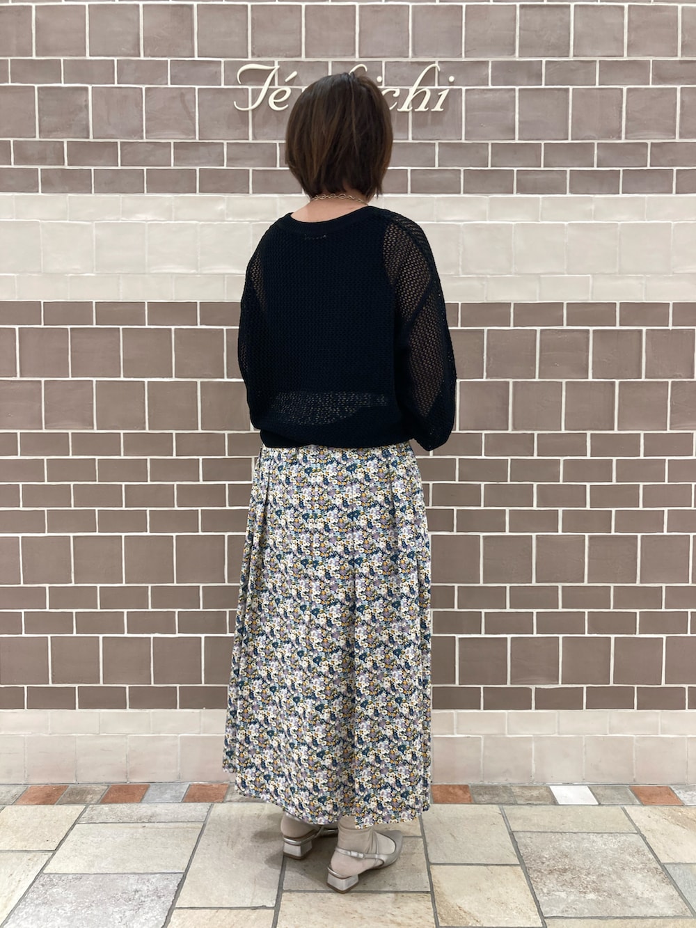 ブラック系のニット/セーター、ブルー系のスカート、シルバー系のパンプスを着用したレディースの春コーディネートの4枚目の写真