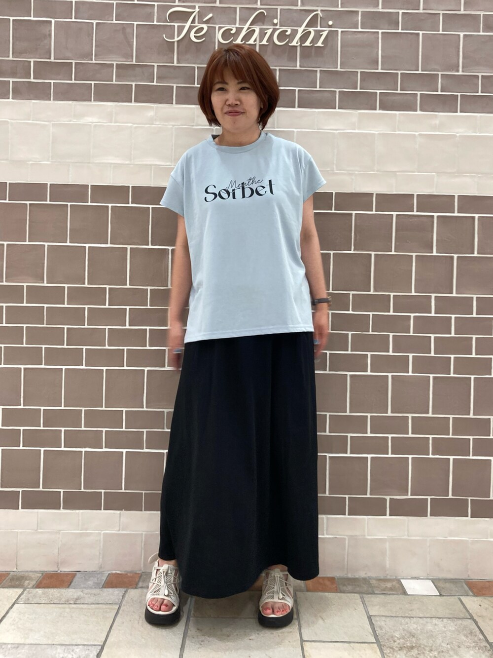 ブルー系のTシャツ/カットソー、ブラック系のスカートを着用したレディースの夏コーディネートの2枚目の写真