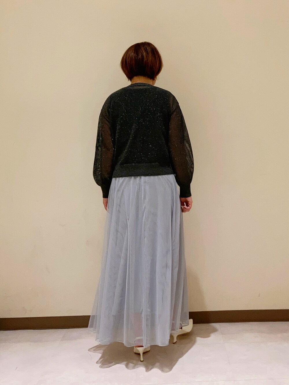 グレー系のカーディガン/ボレロ、グレー系のスカート、ブラック系のタンクトップを着用したレディースの春コーディネートの4枚目の写真