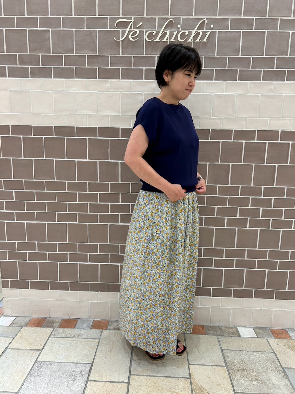 ブルー系のニット/セーター、イエロー系のスカートを着用したレディースの夏コーディネートの2枚目の写真