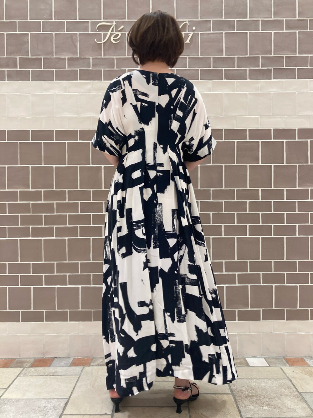 ブラック系のワンピース/ドレス、シルバー系のハンドバッグ、ブラック系のサンダルを着用したレディースの春コーディネートの4枚目の写真