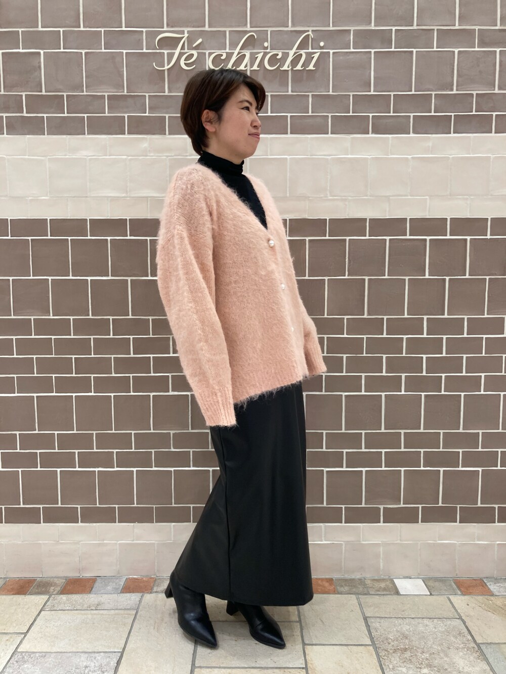 ピンク系のカーディガン/ボレロ、ブラック系のスカートを着用したレディースの冬コーディネートの2枚目の写真