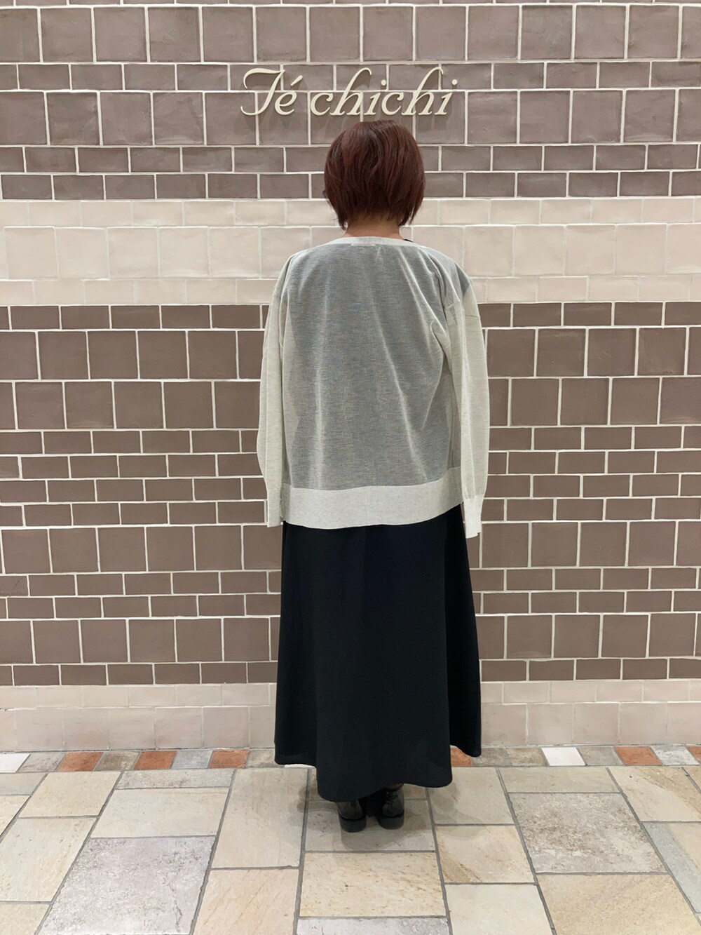 ブラック系のワンピース、ホワイト系のハンドバッグ、グレー系のカーディガン/ボレロを着用したレディースの夏コーディネートの3枚目の写真