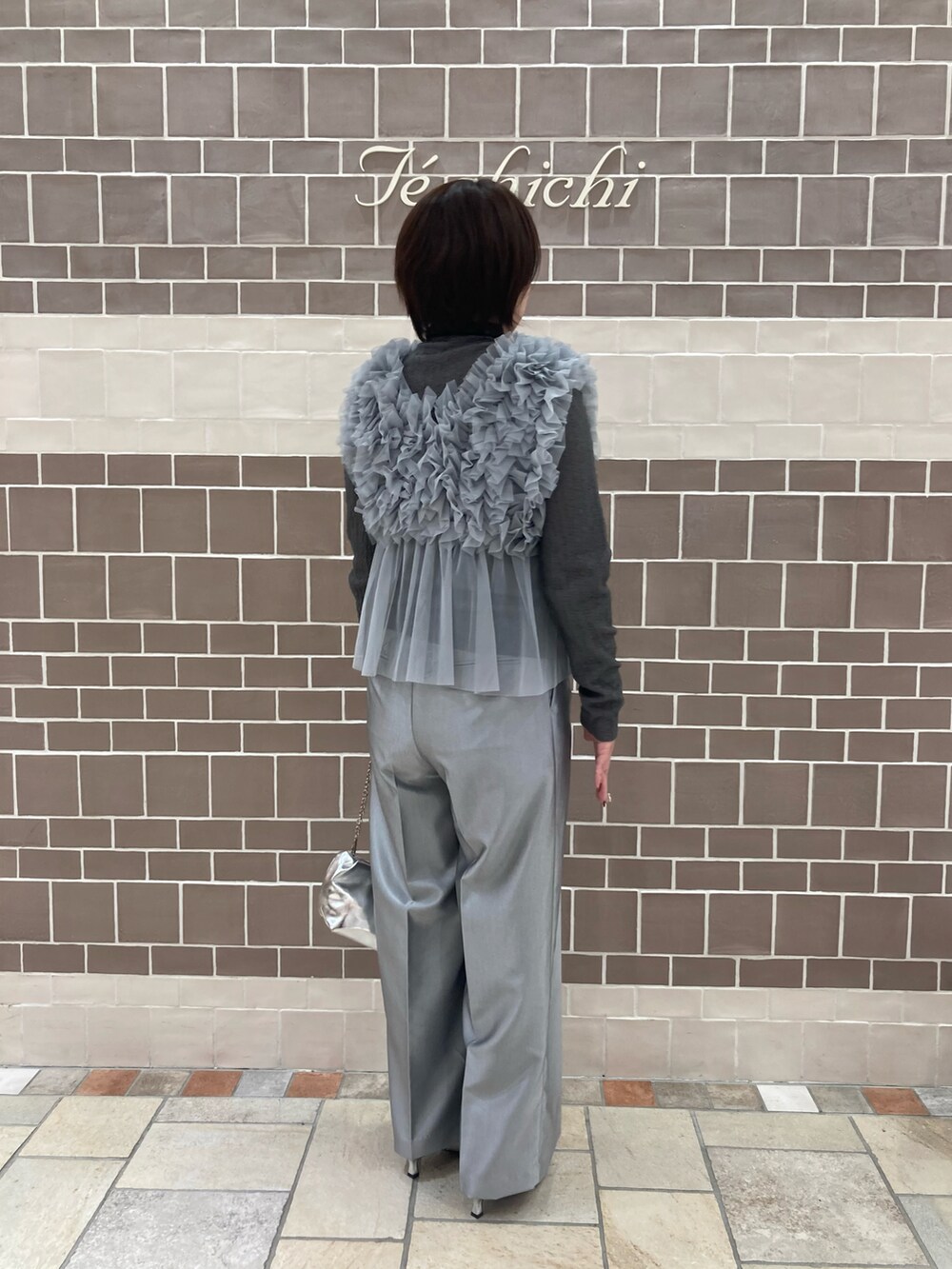 グレー系のニット/セーター、シルバー系のハンドバッグを着用したレディースの秋コーディネートの3枚目の写真