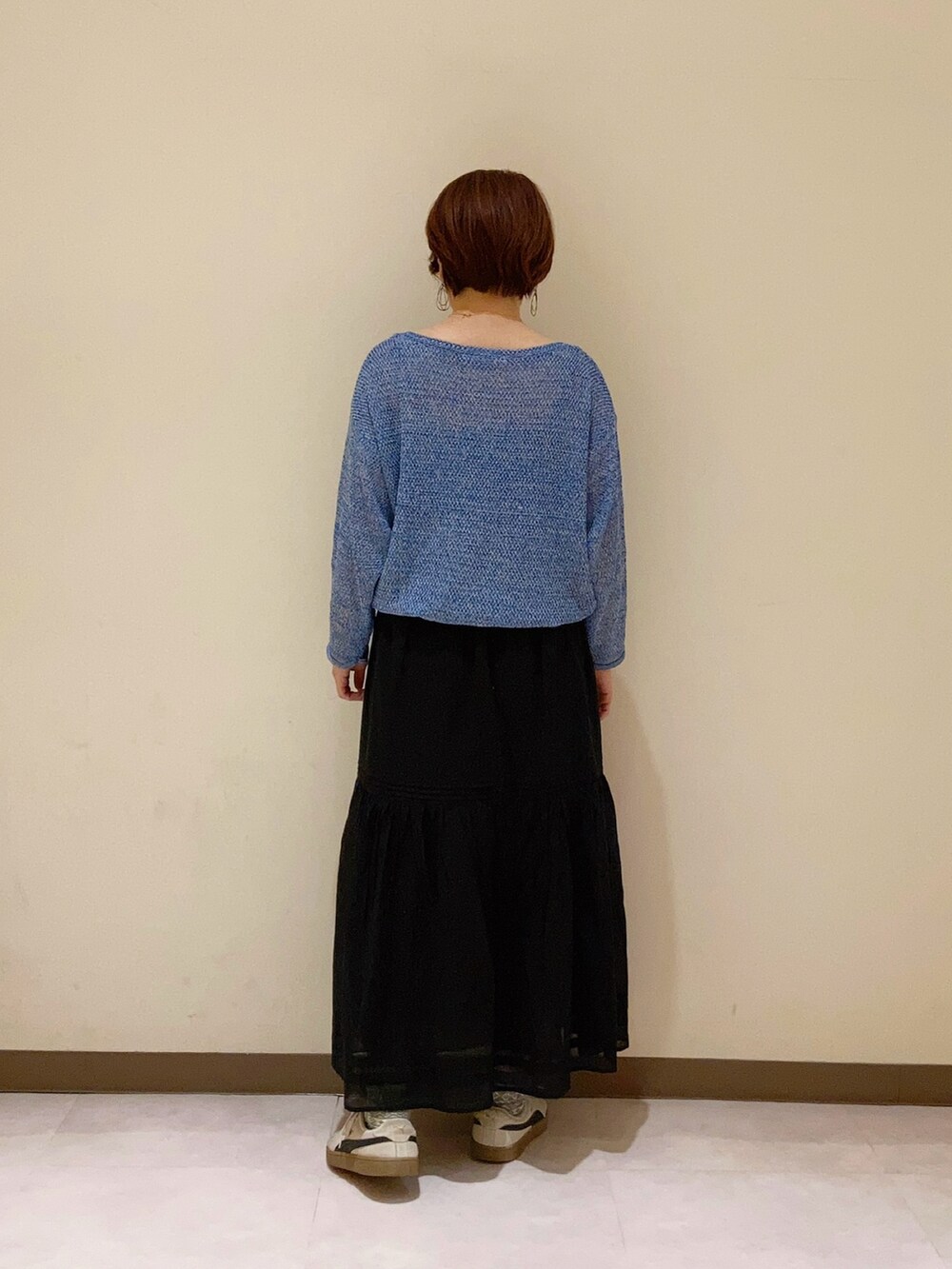 ブルー系のニット/セーター、ブラック系のスカートを着用したレディースの春コーディネートの5枚目の写真