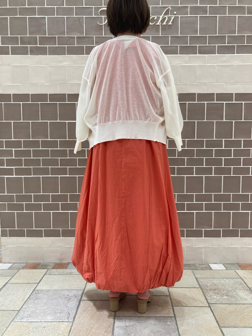 ホワイト系のカーディガン/ボレロ、オレンジ系のワンピース/ドレス、ベージュ系のハンドバッグを着用したレディースの春コーディネートの4枚目の写真