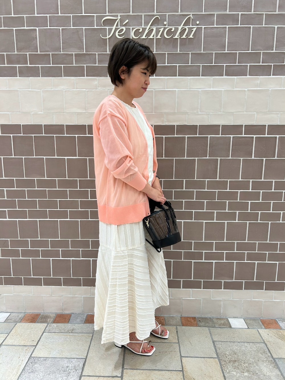 ホワイト系のワンピース、ピンク系のカーディガン/ボレロ、ホワイト系のサンダルを着用したレディースの夏コーディネートの3枚目の写真