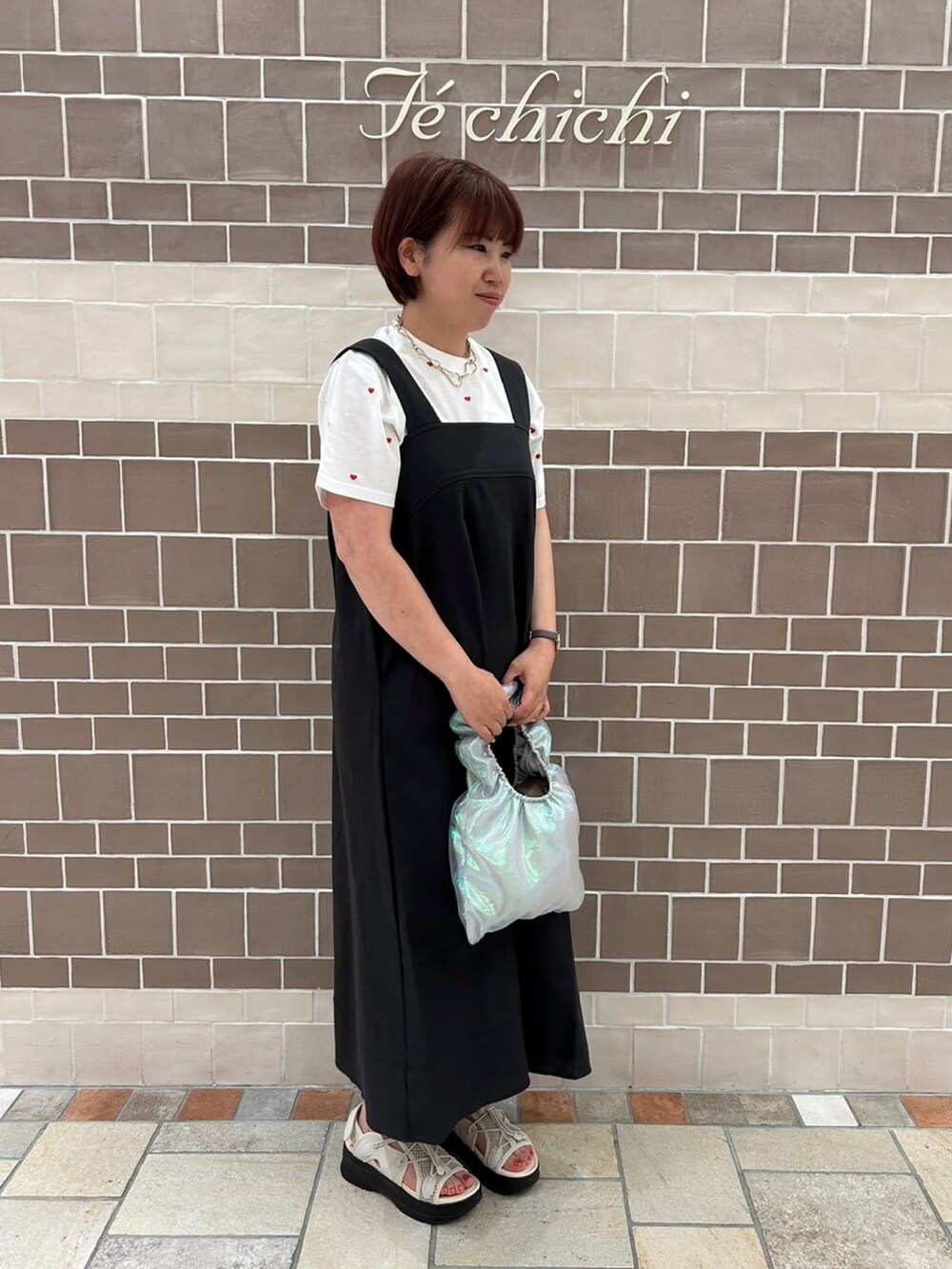 ブラック系のワンピース/ドレス、レッド系のTシャツ/カットソー、シルバー系のハンドバッグを着用したレディースの春コーディネートの2枚目の写真