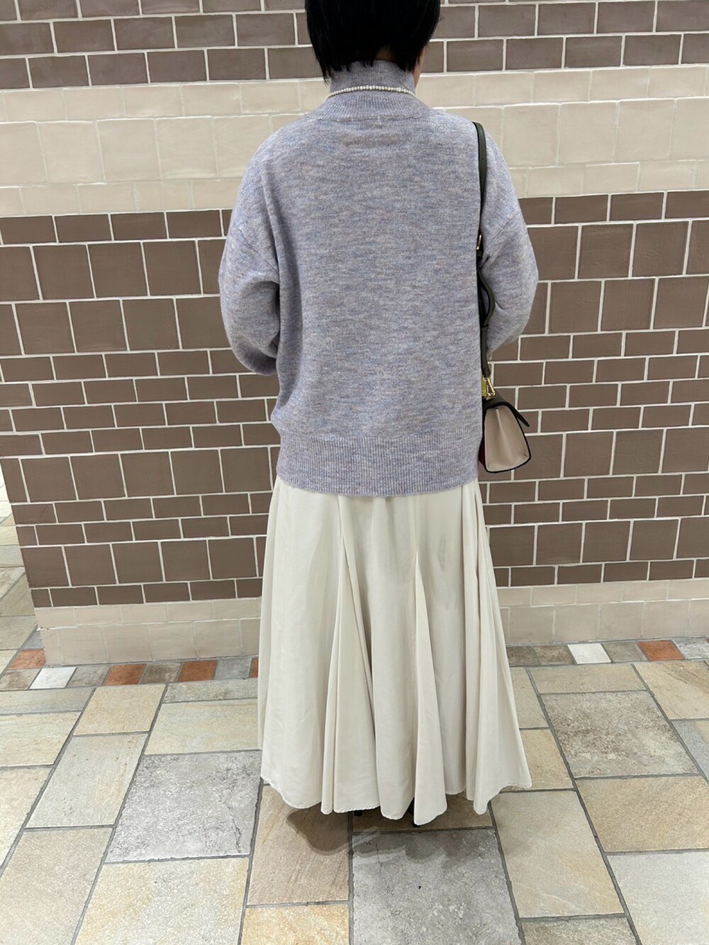 パープル系のニット/セーター、ピンク系のハンドバッグ、ホワイト系のスカートを着用したレディースの冬コーディネートの3枚目の写真