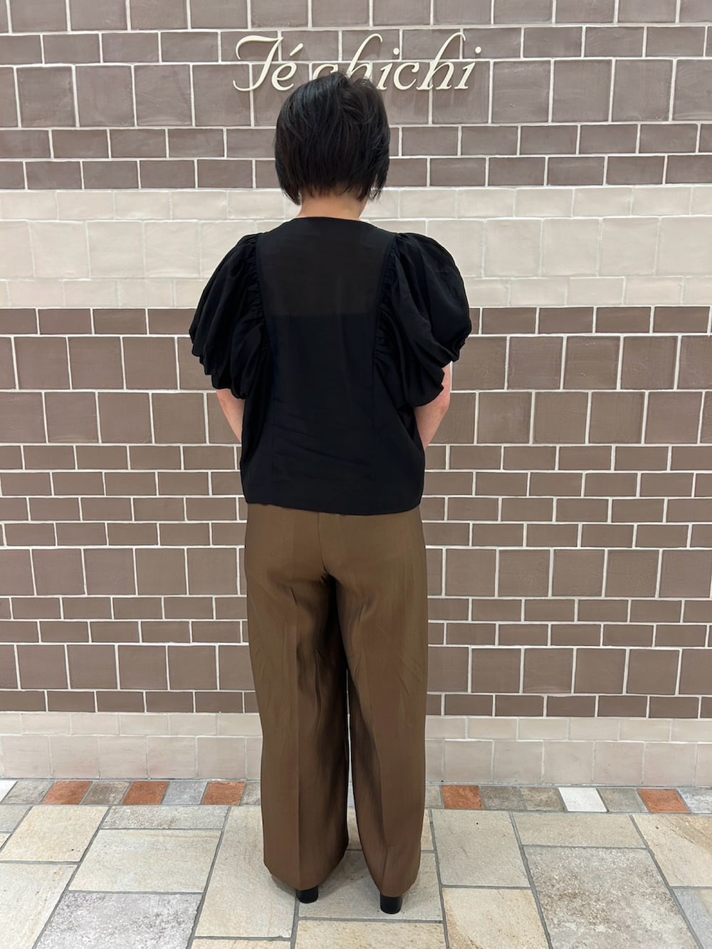 ブラック系のシャツ/ブラウス、ブラウン系のパンツ、ゴールド系のハンドバッグを着用したレディースの夏コーディネートの4枚目の写真