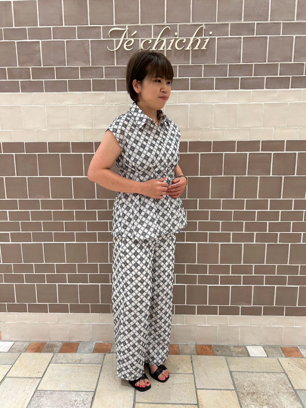 ホワイト系のシャツ/ブラウス、ホワイト系のパンツ、ブラック系のサンダルを着用したレディースの夏コーディネートの2枚目の写真